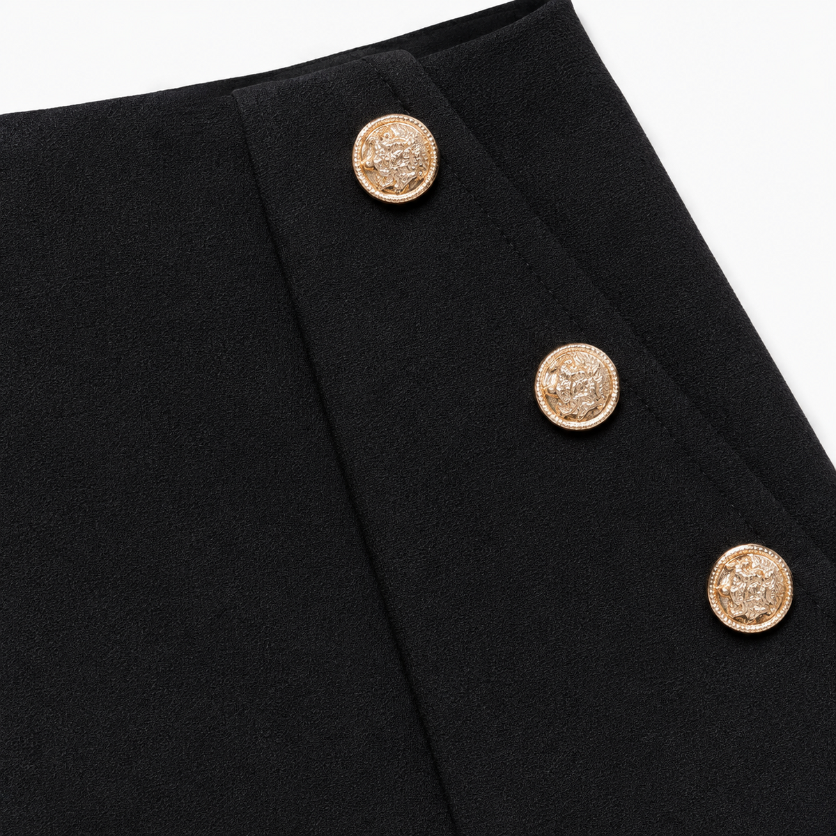 Detalle de tela y botones dorados del short negro